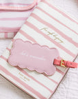 Pink and white striped travel pouch with a cloud-shaped tag on a light background