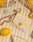 Decorative items including a lemon, keychain, and small pouch on a striped surface.