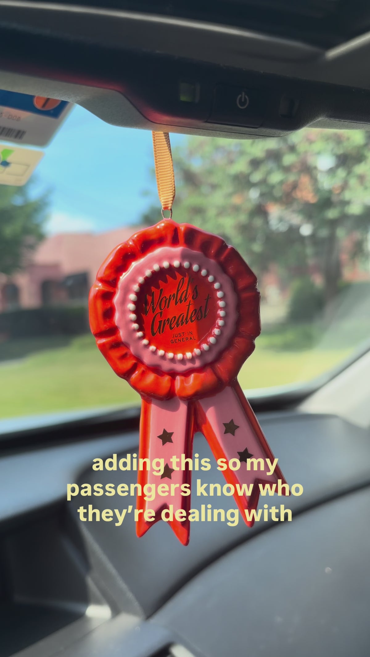 ornament ribbon hanging from rearview mirror and says 'adding this so my passengers know who they're dealing with.'