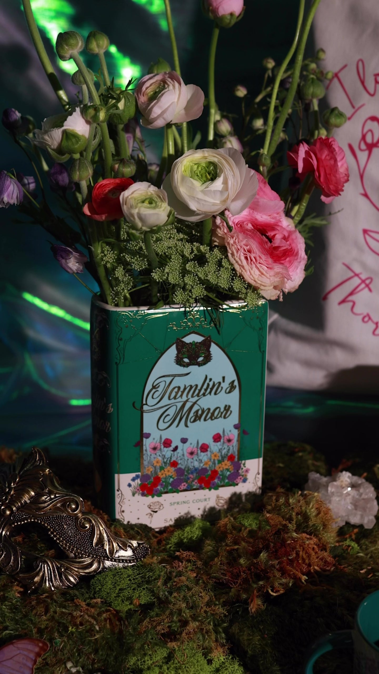 Book-shaped vase with 'Tamlin's Manor' design with flowers inside