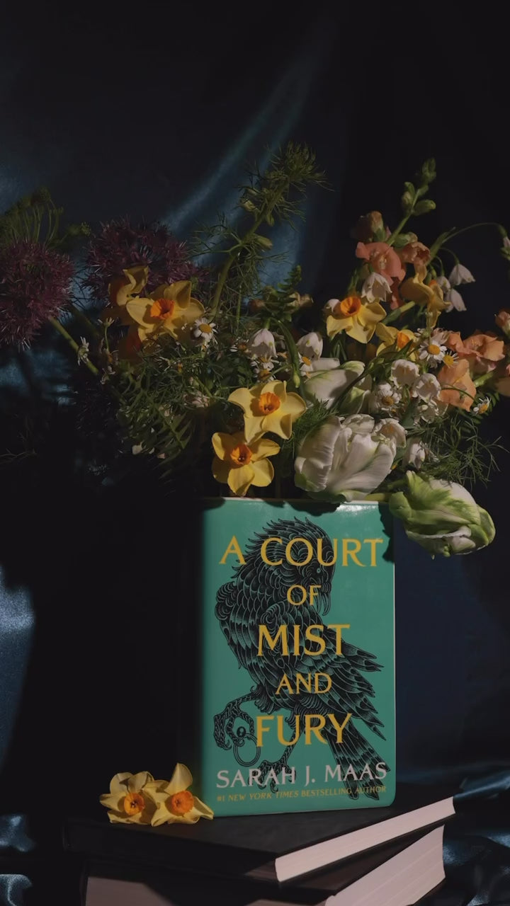 A Court of Mist and Fury' by Sarah J. Maas vase with a green cover and white spine and a bouquet inside