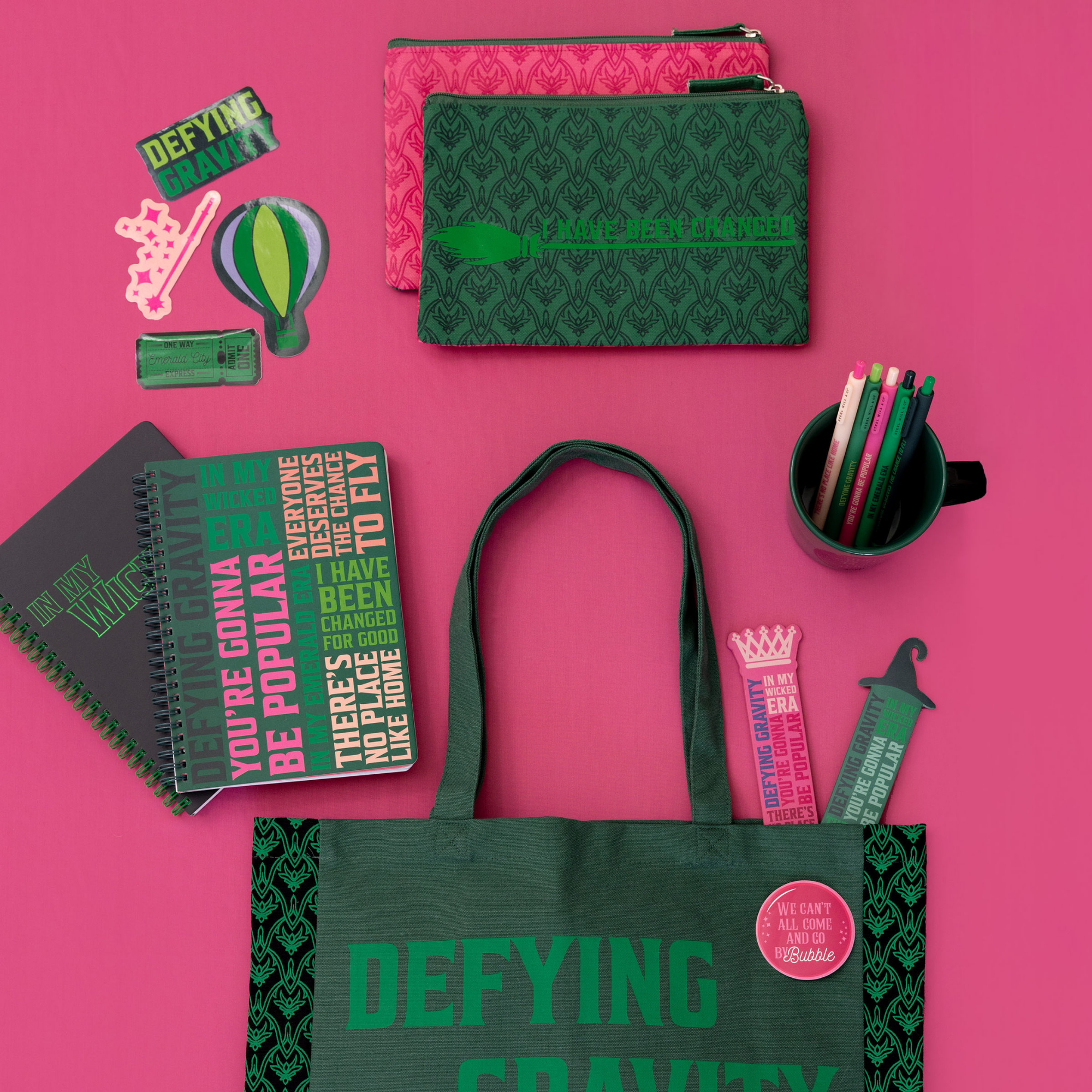 Collection of green and pink stationery items on a pink background